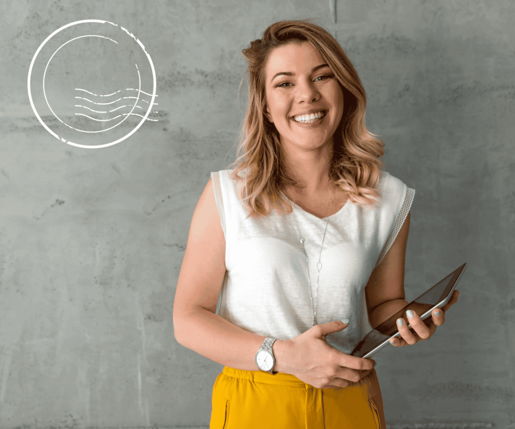 Geschäftsadresse mieten/ junge Frau lächelt in die Kamera und hält ein Tablet. Sie trägt eine gelbe Hose.